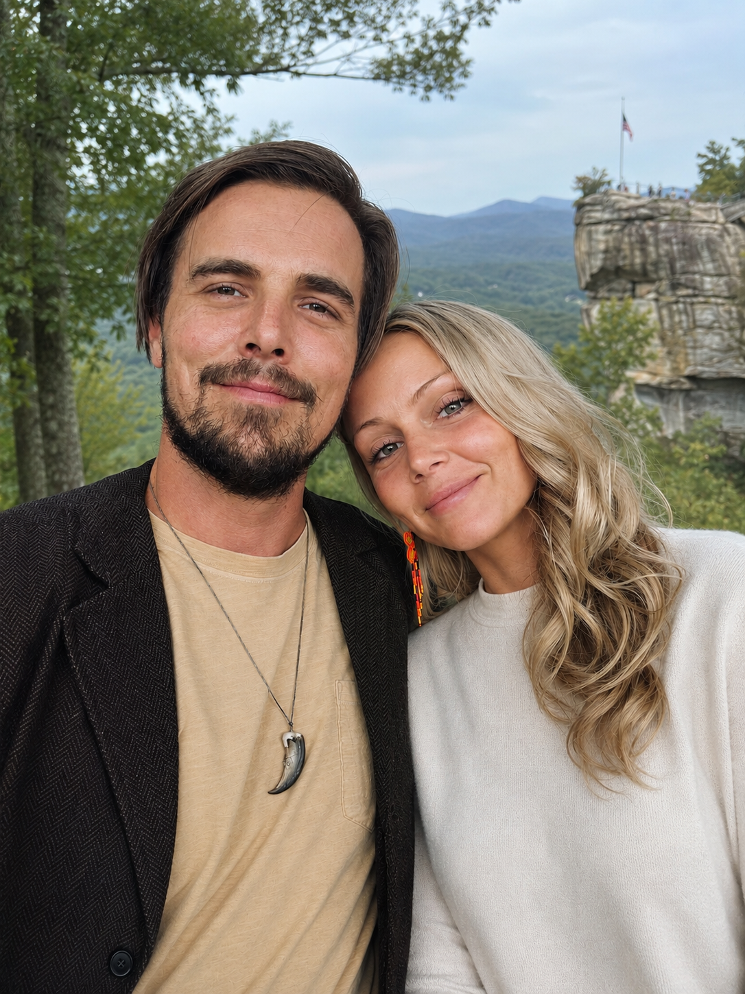 The husband-and-wife owners of Roots Revival, smiling together with Chimney Rock in the background